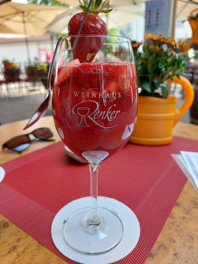Weinglas mit Renker-Gravur und fruchtiger Bowle auf einem Tisch der Terrasse